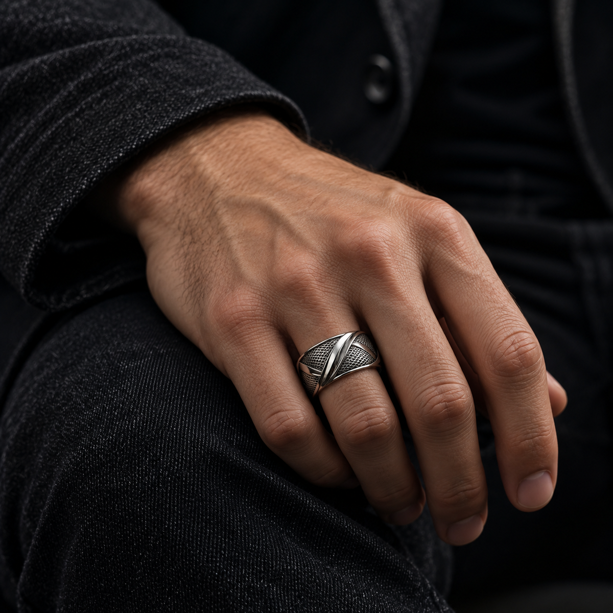 Male hand resting on dark jeans wearing Men's sculptural wire mesh statement band
