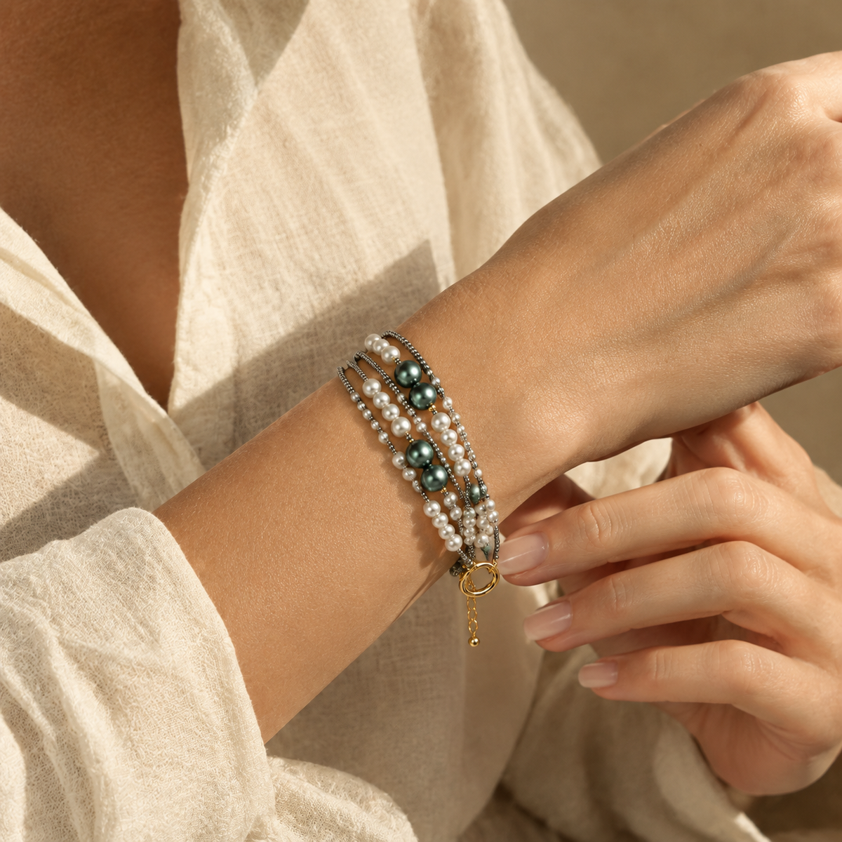 Model wearing the multi-strand faux pearl and green beaded bracelet paired with an elegant white linen outfit.
