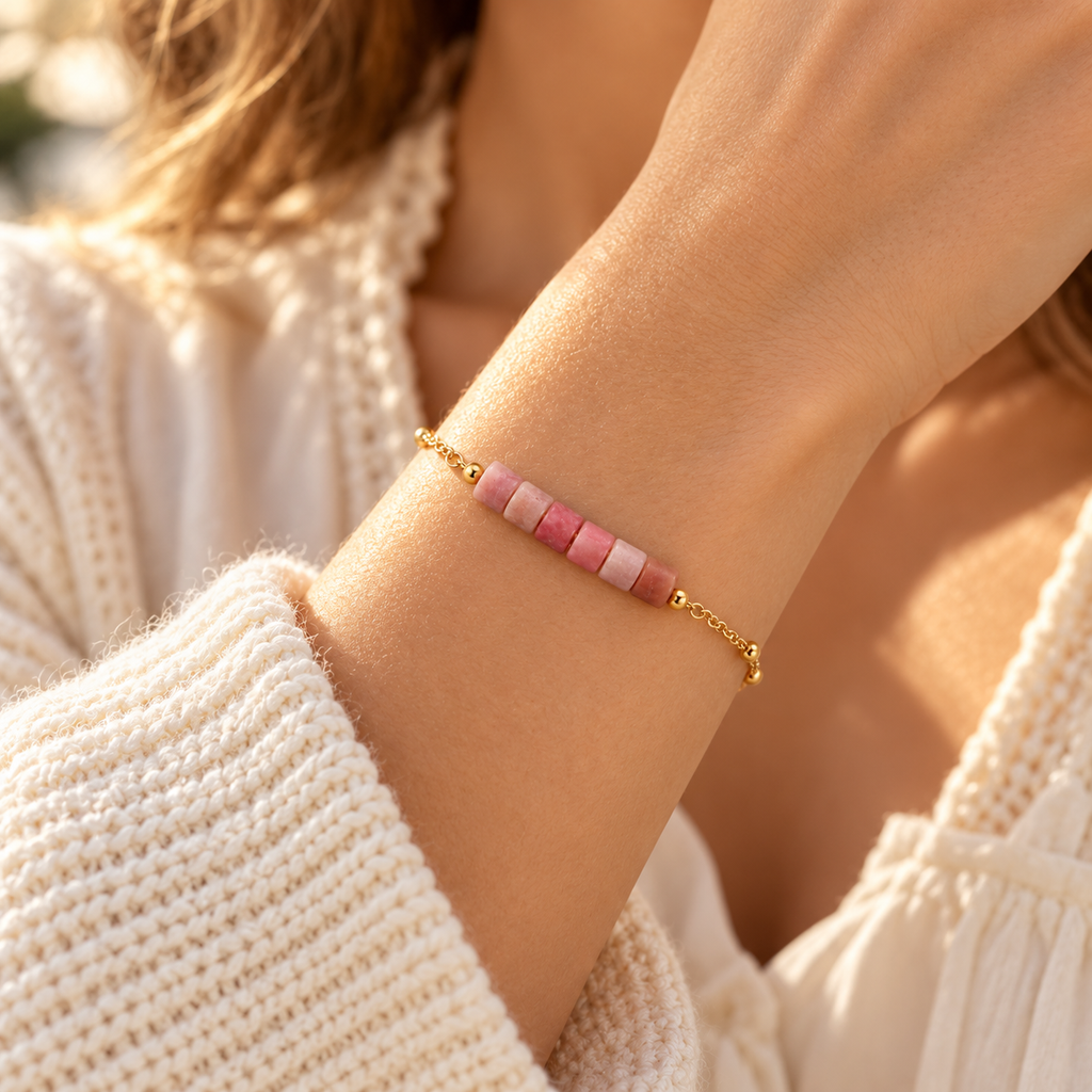 Side angle wrist shot of the delicate pastel pink gemstone bar bracelet paired with an ivory knit sweater.
