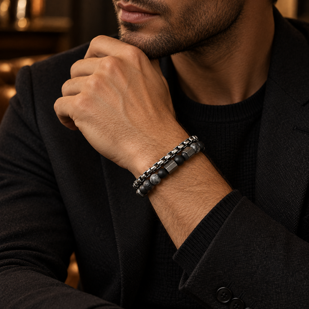 Gentleman in black suit touching chin showing double-strand hematite and chain bracelet
