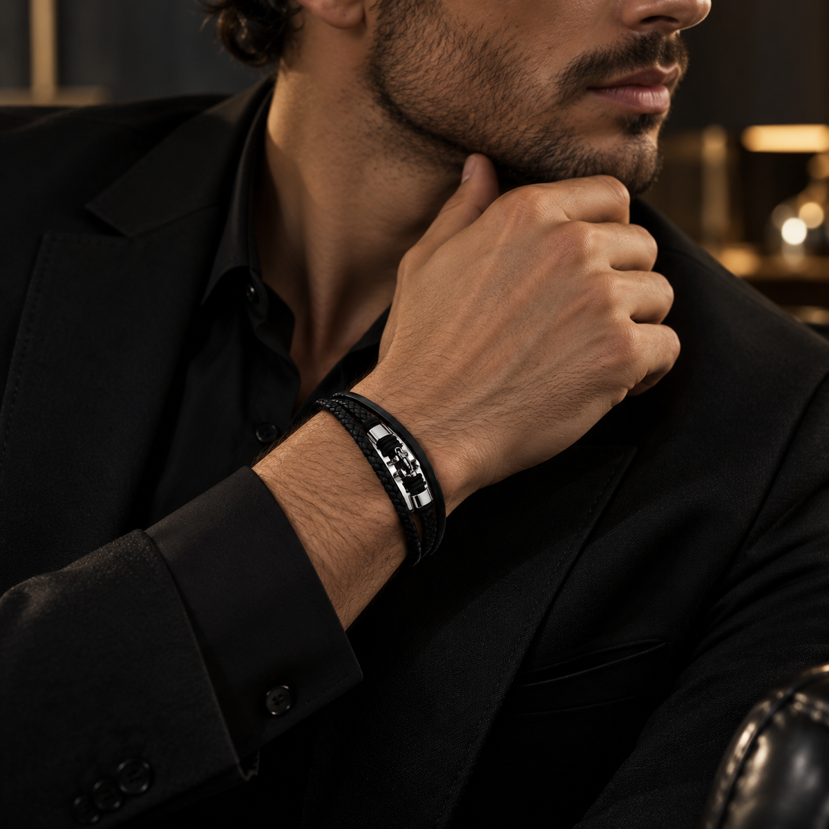 Handsome male model in all-black formal wear showing nautical stainless steel bracelet
